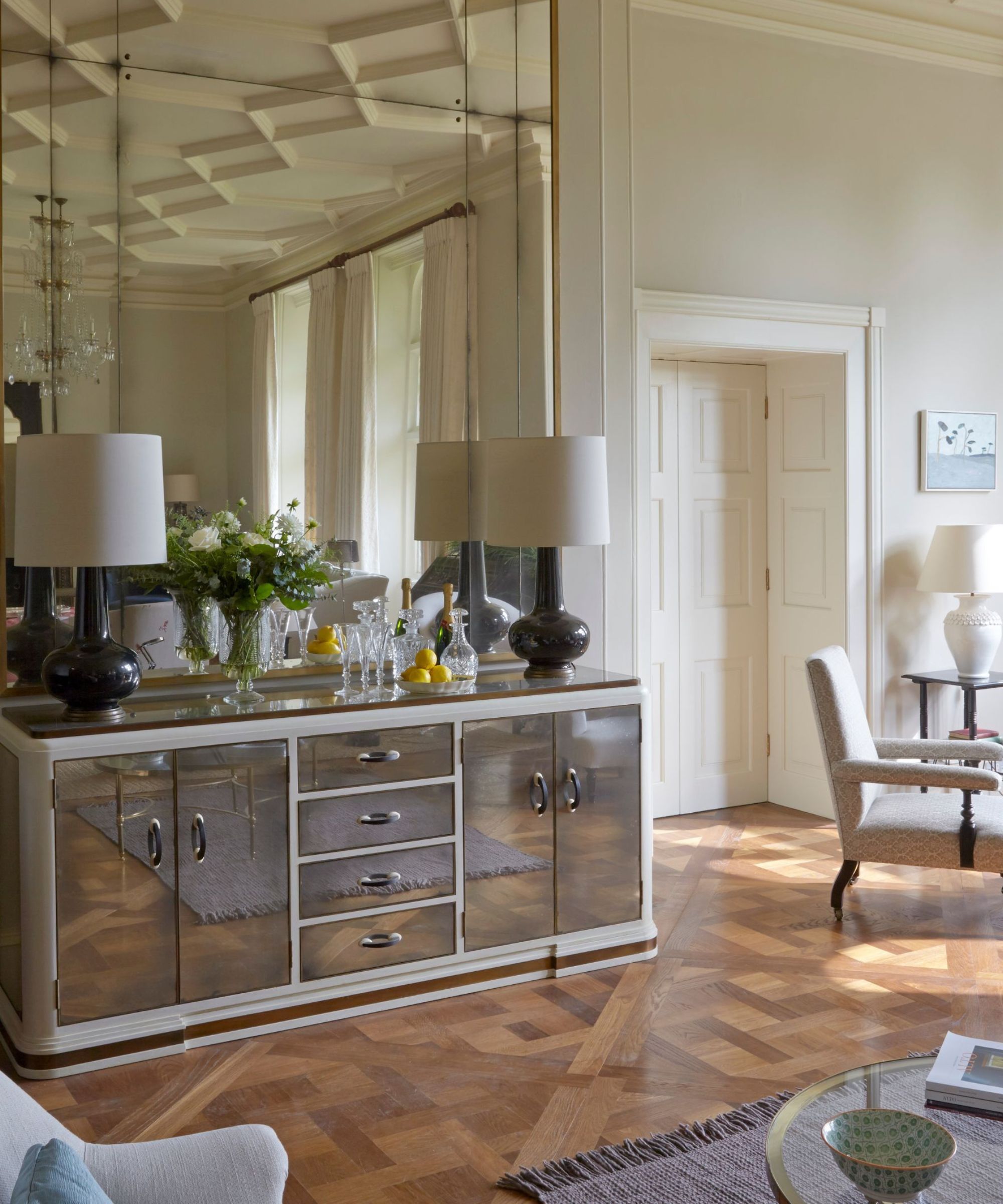 mur d'accent miroir dans une salle à manger neutre traditionnelle avec une console en acier inoxydable en miroir stylé avec une paire de lampes