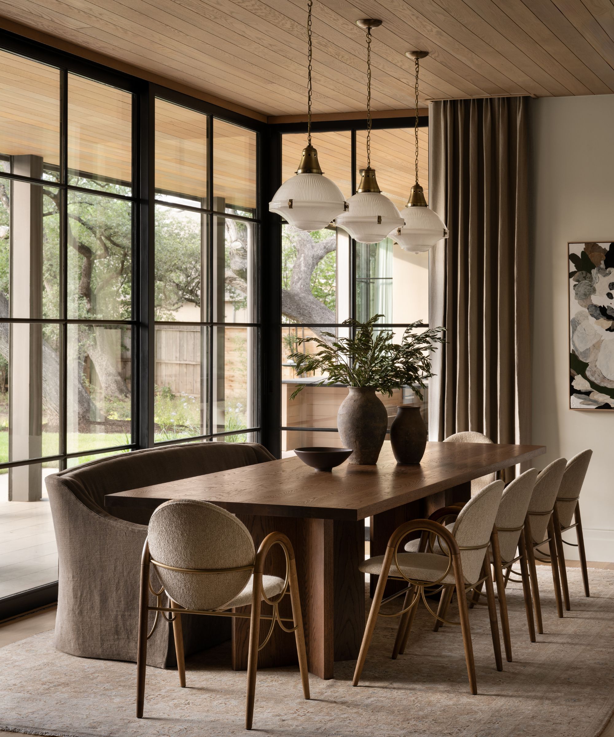 Salle à manger neutre avec table à manger en bois, chaises boucle et canapé en lin, pendentif en verre et grandes fenêtres