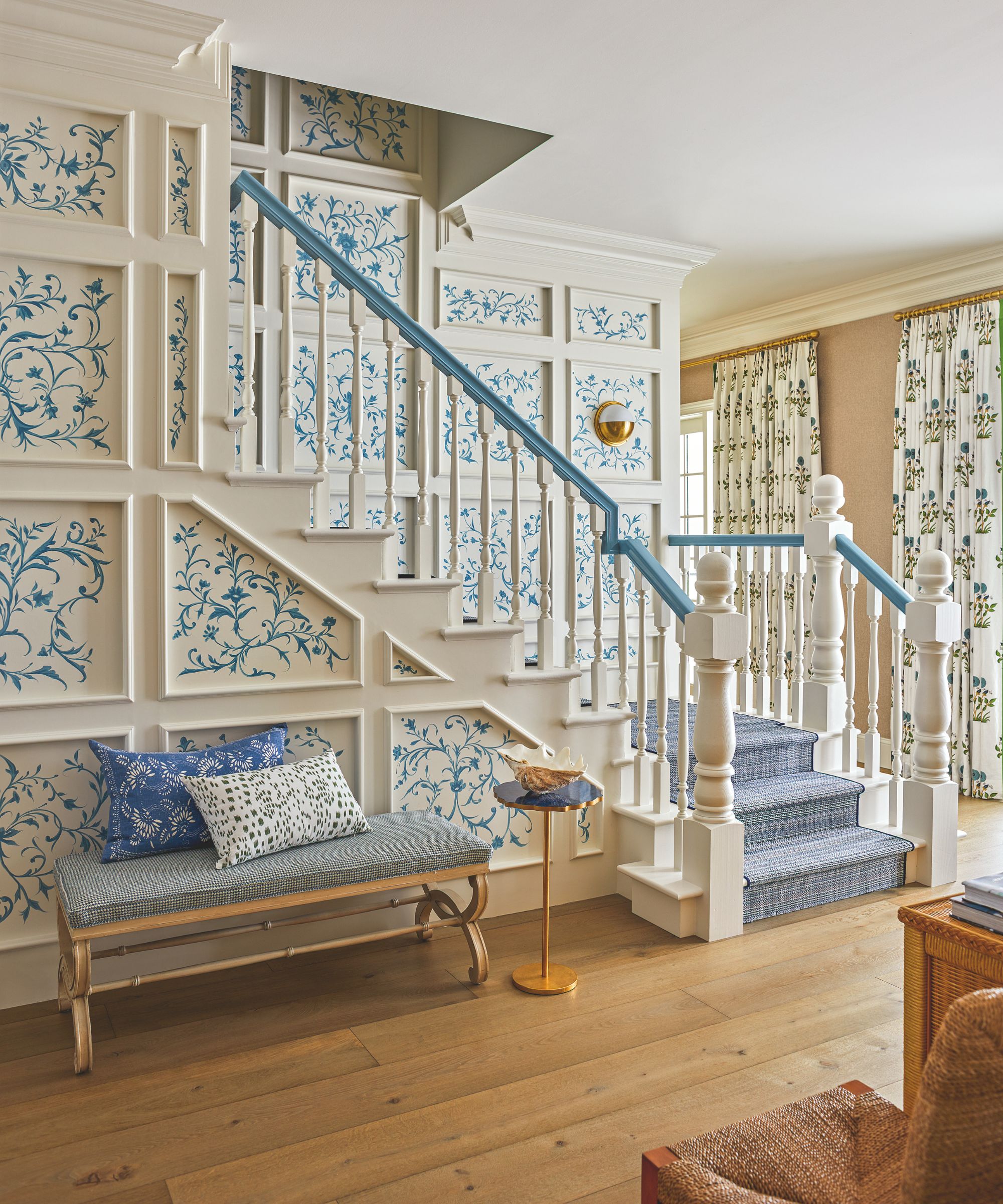couloir avec panneaux muraux à motifs et escalier et plancher en bois et banisters bleus