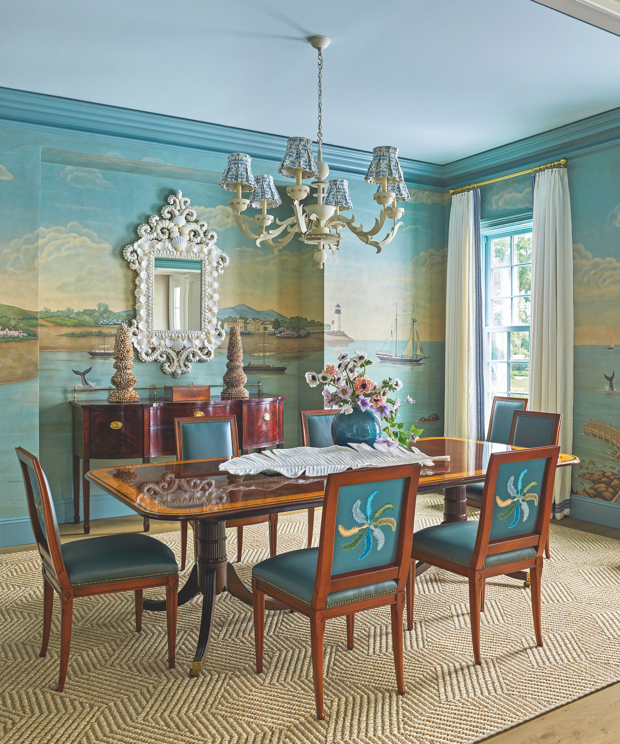 Salle à manger avec chaises en cuir rembourrées bleues et table à manger en bois et tapis de jute et couverture murale illustrée