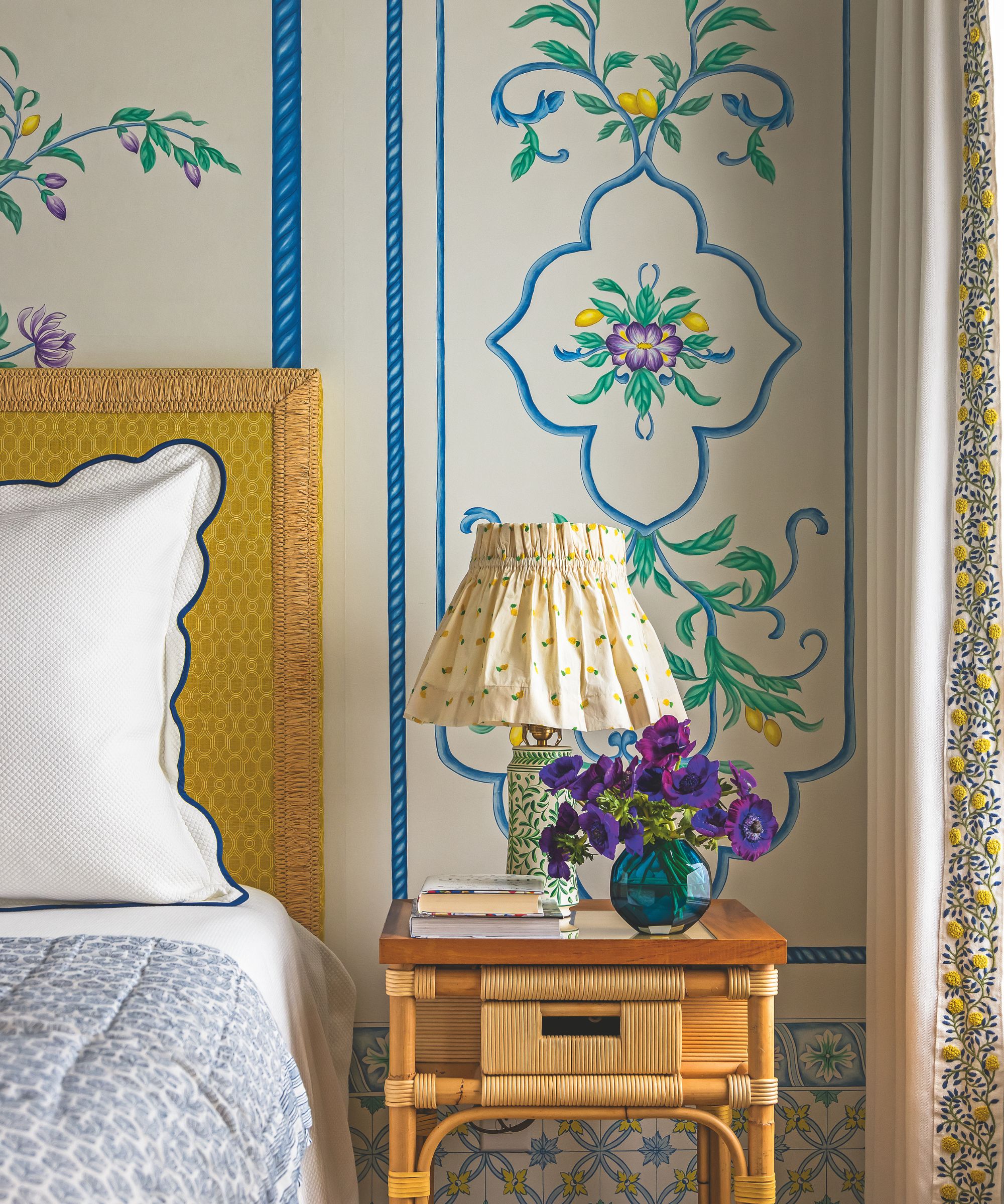 Chambre avec papier peint illustré et table de chevet de rotin et abat-jour en tissu
