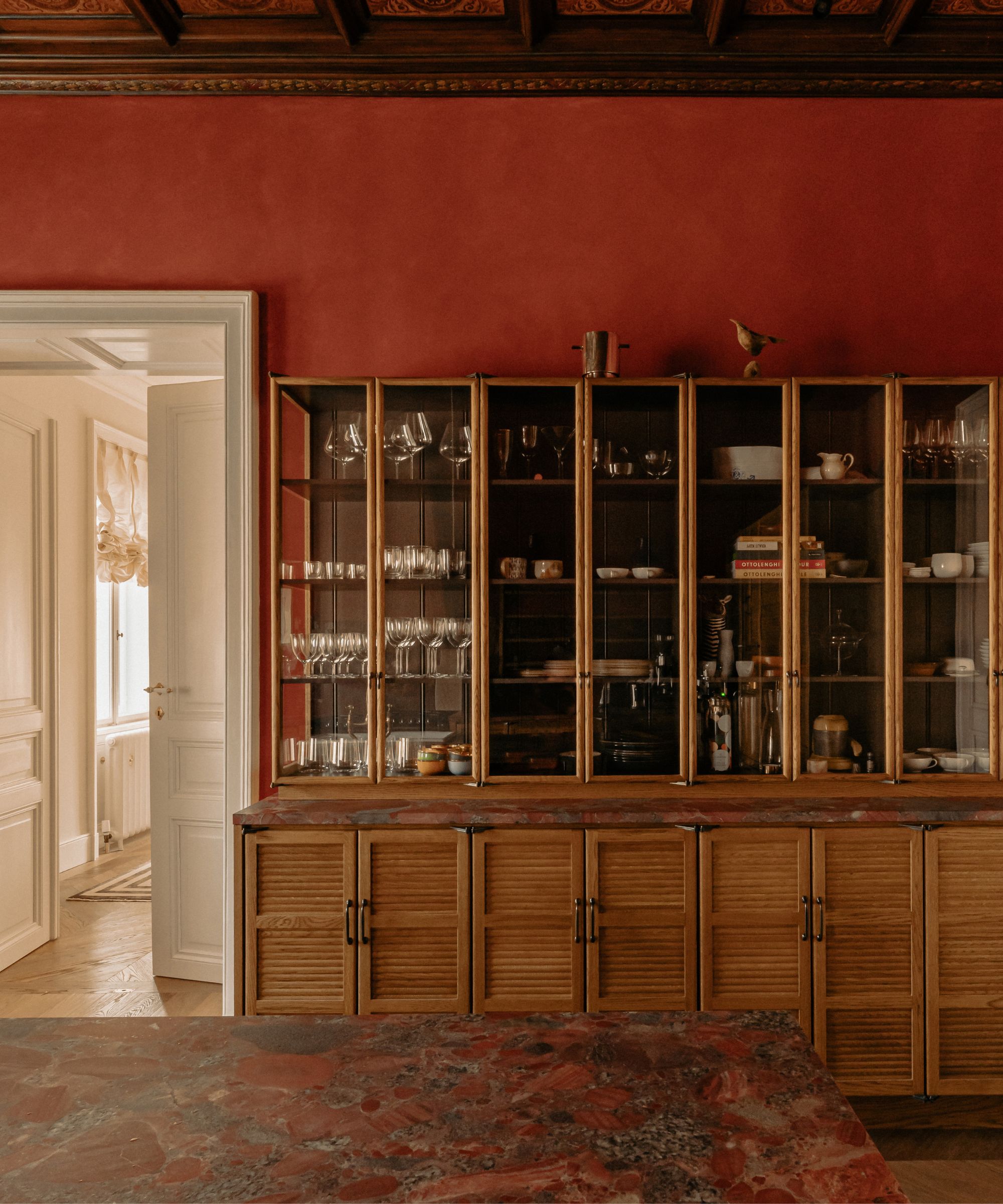 Une cuisine rouge paprika avec des armoires inférieures en bois et des armoires supérieures en verre