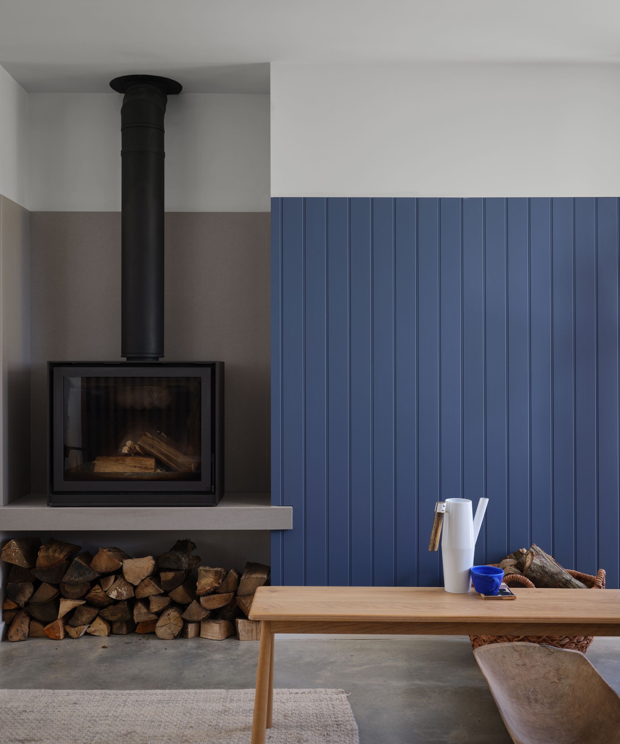 Une pièce avec un mur lambrissé peint en bleu doux, un poêle à bois contre un mur peint dans une taupe brun
