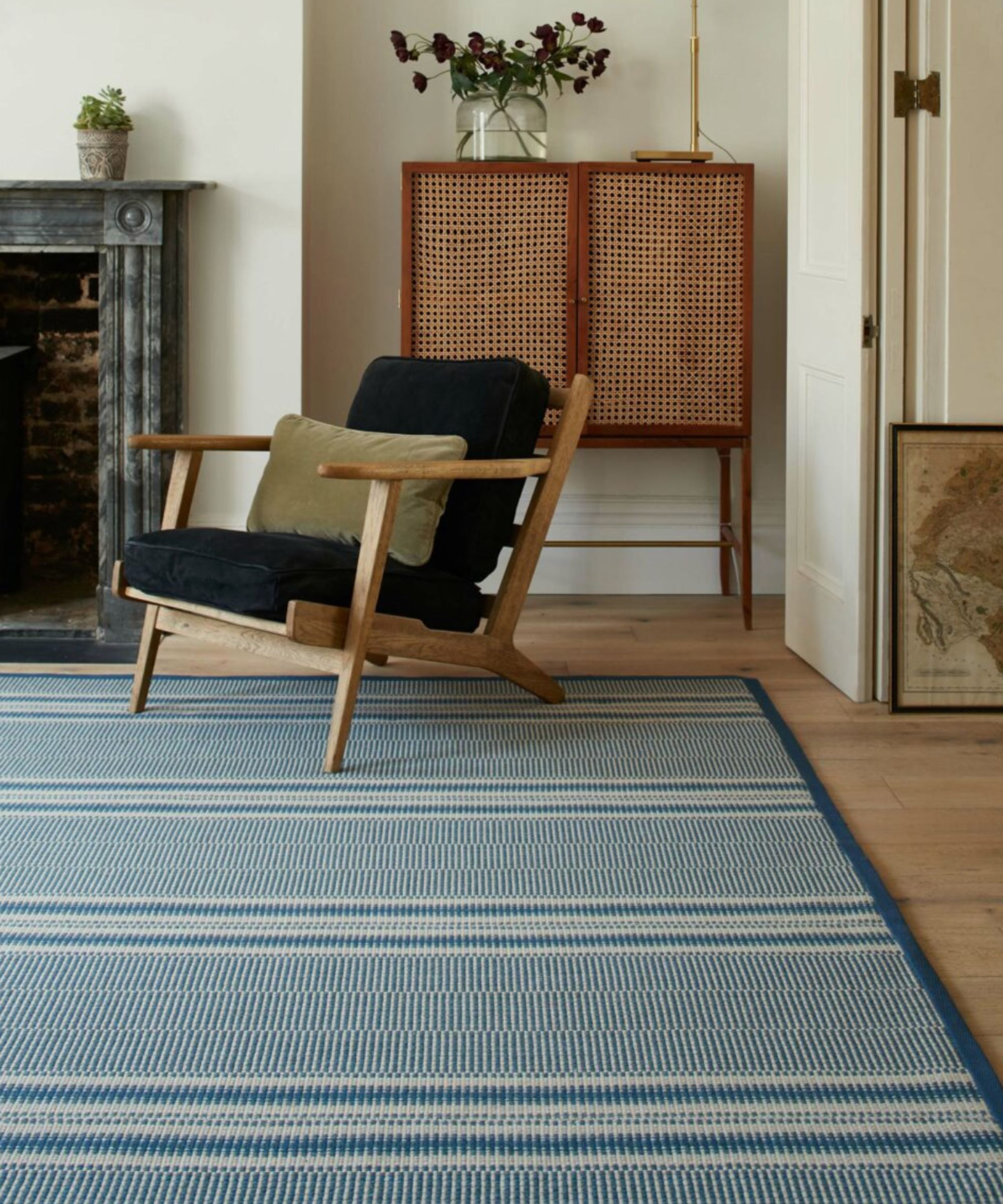Une pièce neutre avec un tapis bleu et une chaise bleue avec une armoire en bois