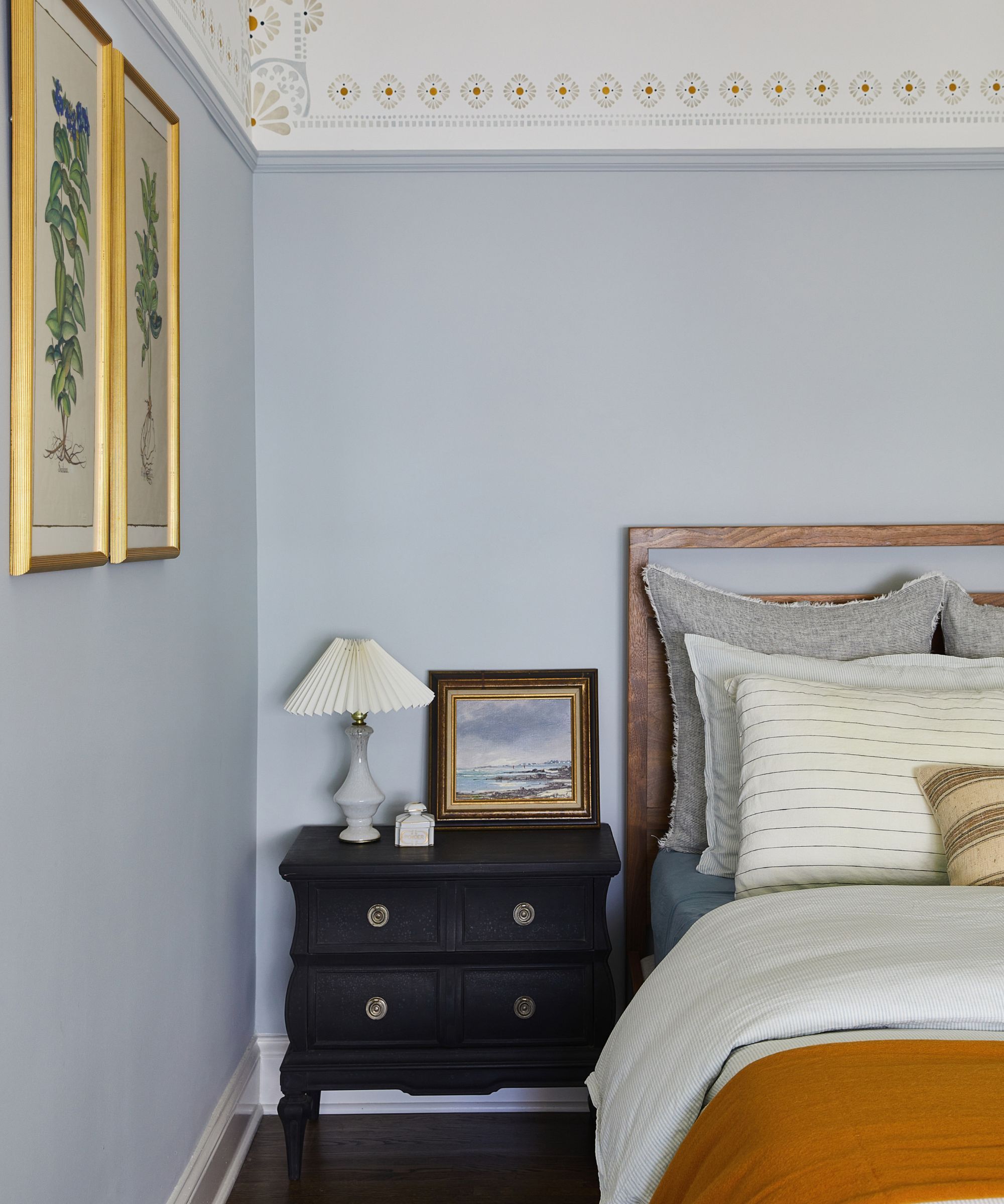 Une chambre bleu pâle avec une table d'appoint noire, la lampe et la peinture