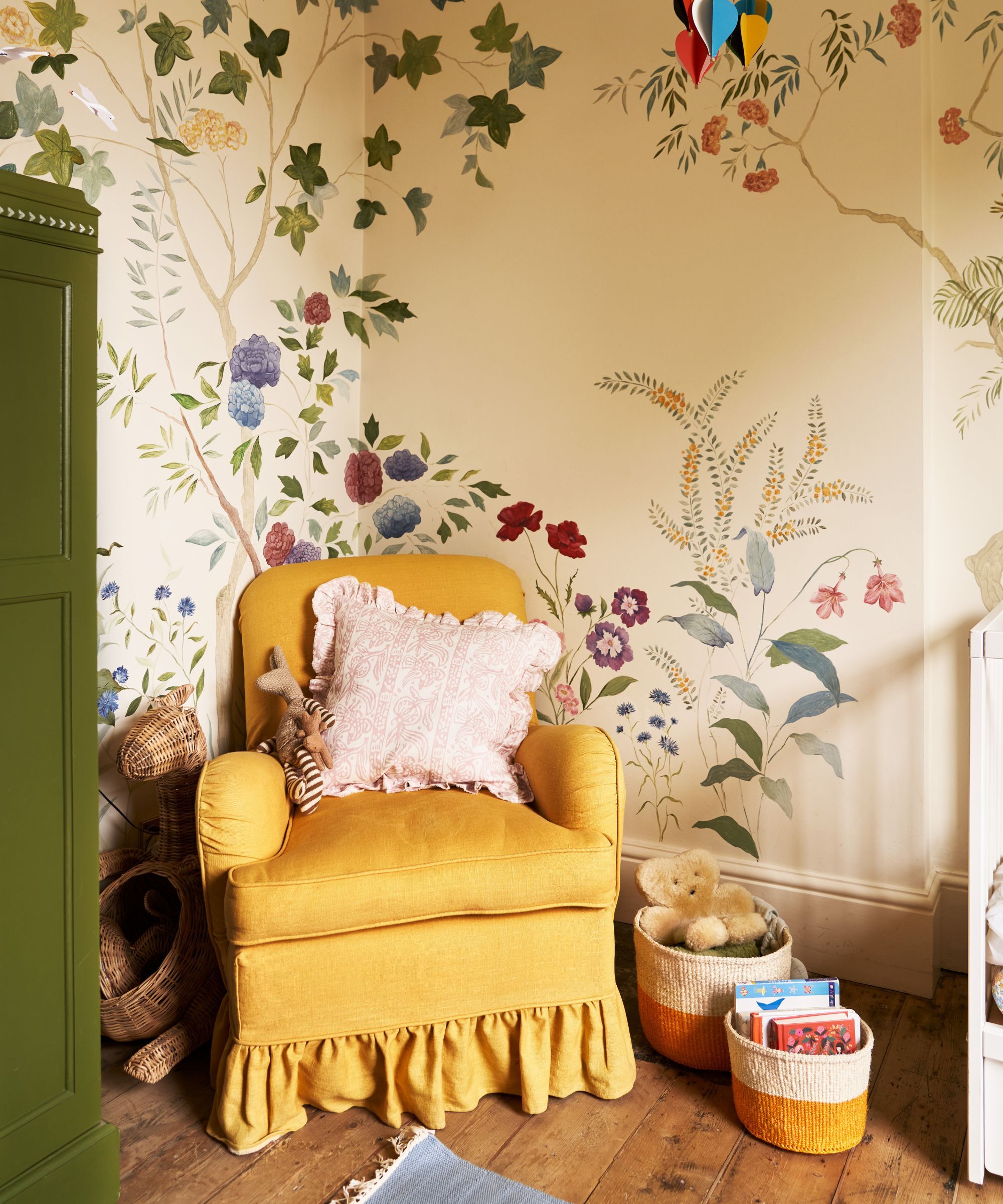 Une crèche d'enfant avec une chaise jaune vif et un mur recouvert d'une fresque murale florale