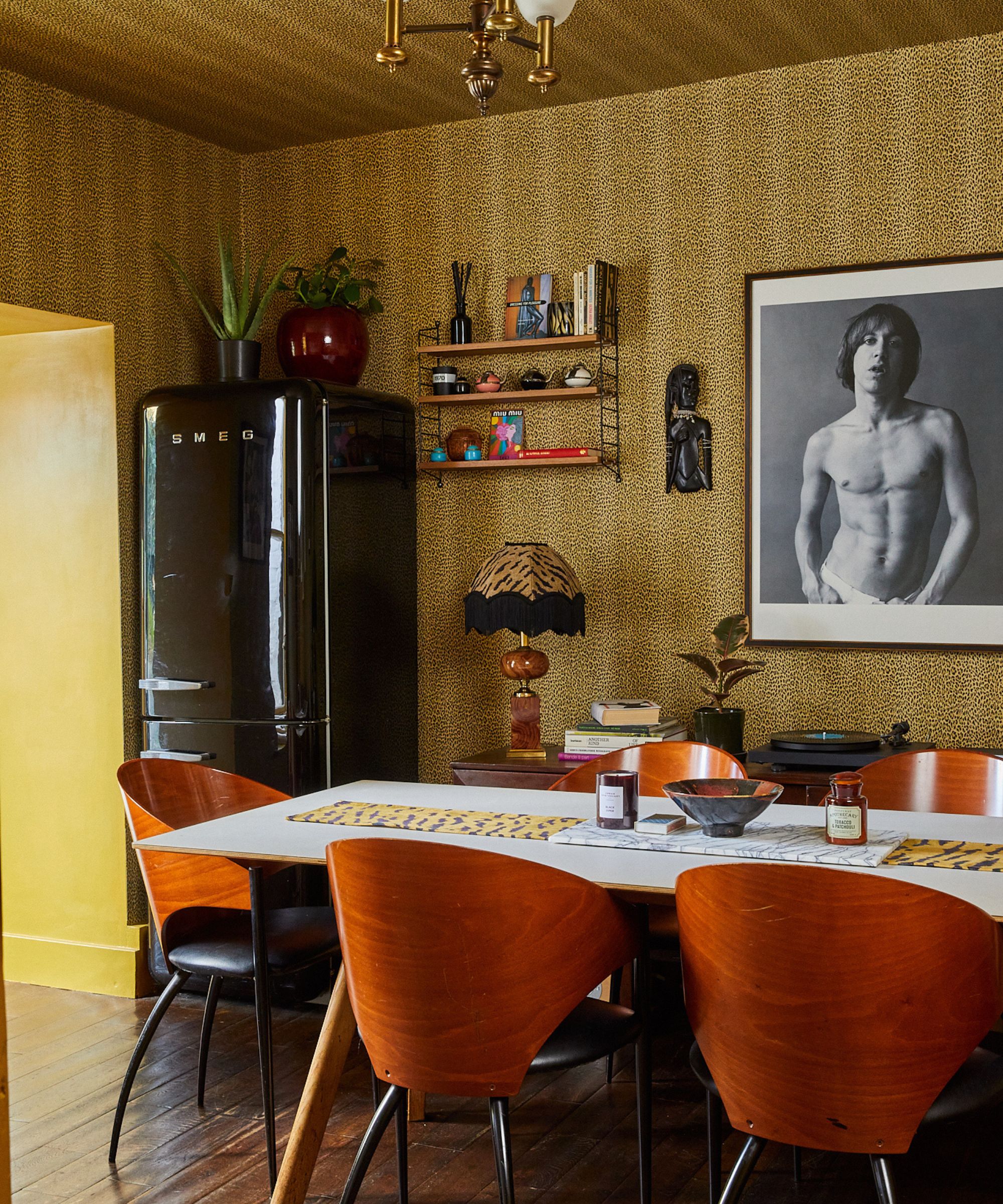 Fond d'écran à imprimé léopard avec table à manger et chaises en bois du milieu du siècle et photographie encadrée
