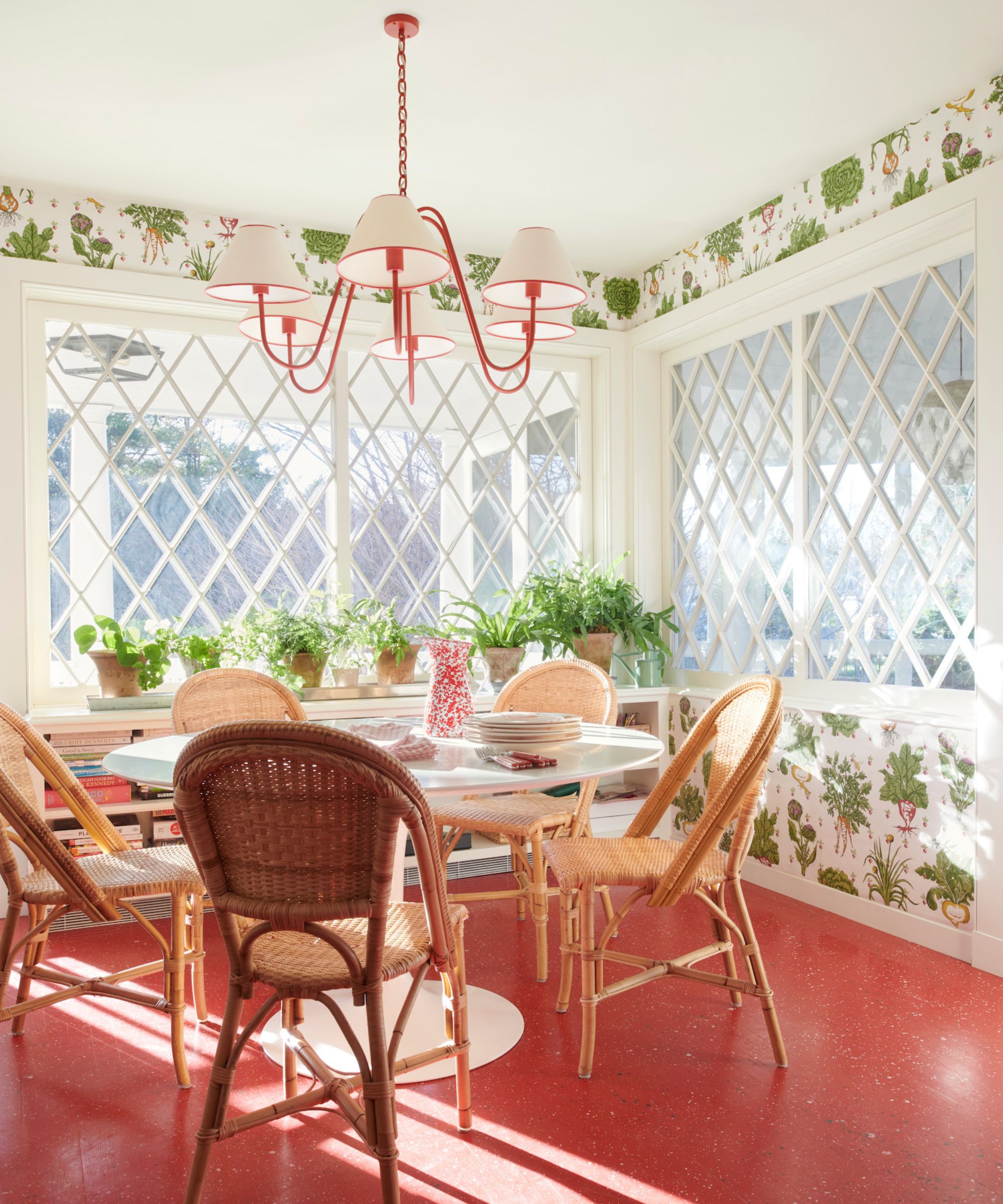 Coin-petit-déjeuner avec table ronde et chaises de salle à manger en rotin et sols rouges, fond d'écran de radis et pendentif rouge et blanc