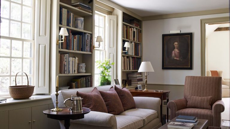 Vos pièces vintage pourraient-elles sortir avec votre maison? Les concepteurs mettent en garde pour éviter ces «coupables familiers qui rendent un espace coincé dans le temps» Traditional living room with sconces, large windows and sofa with bookshelves and antique painting