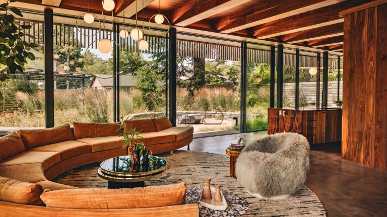 « L’Italie de l’ère discale sexuelle rencontre la ferme japonaise dans la jungle brésilienne » était la description que le designer d’intérieur a donné à cette maison moderniste à paroi de verre glass walled living room with curved sofa
