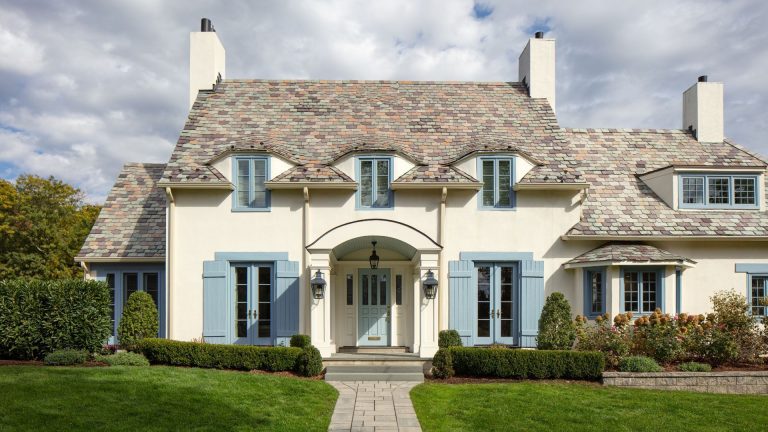 Th exterior of a house painted in an off white with blue doors and windows