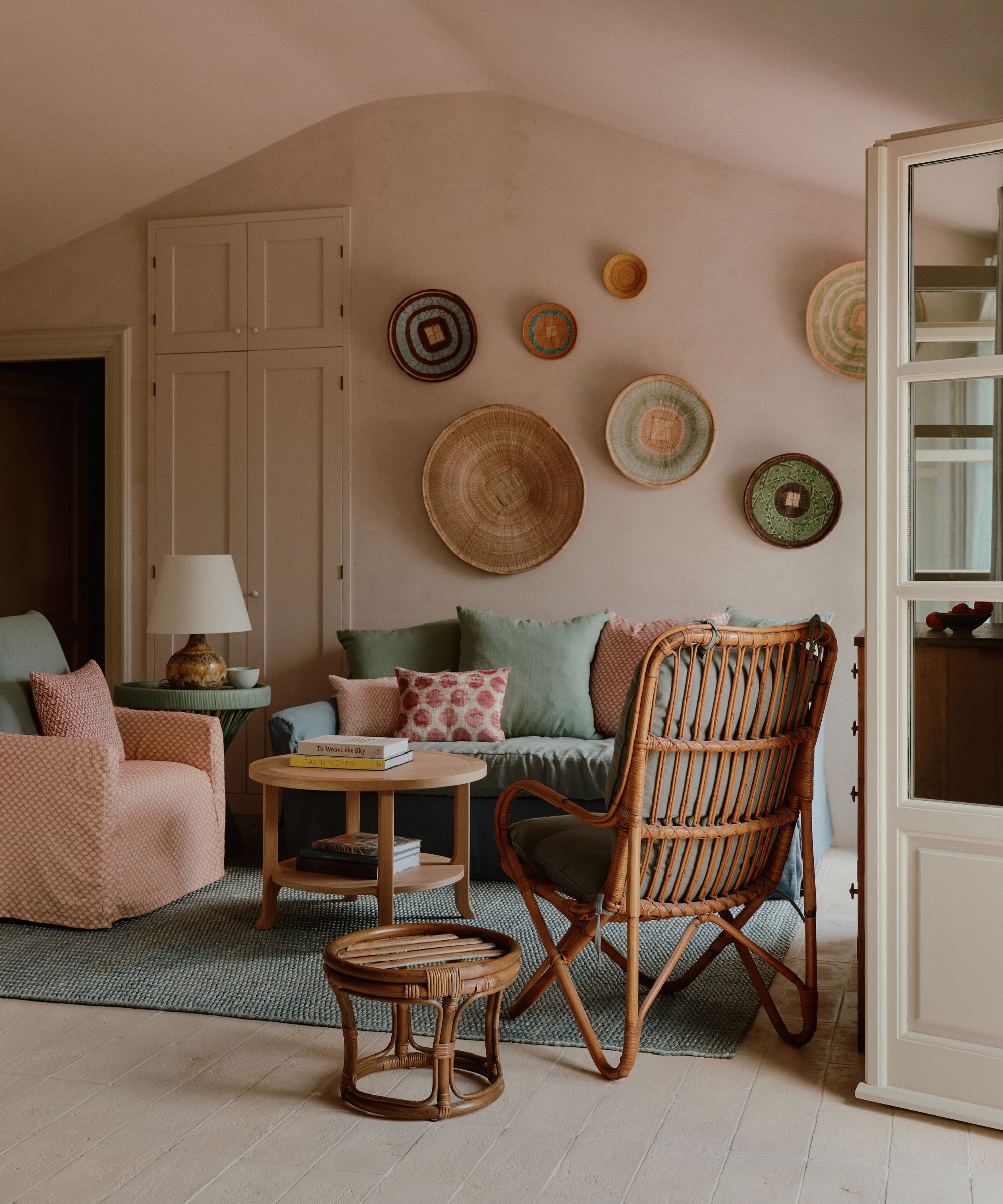 Salon rose pâle avec mur de galerie de décorations de rotin