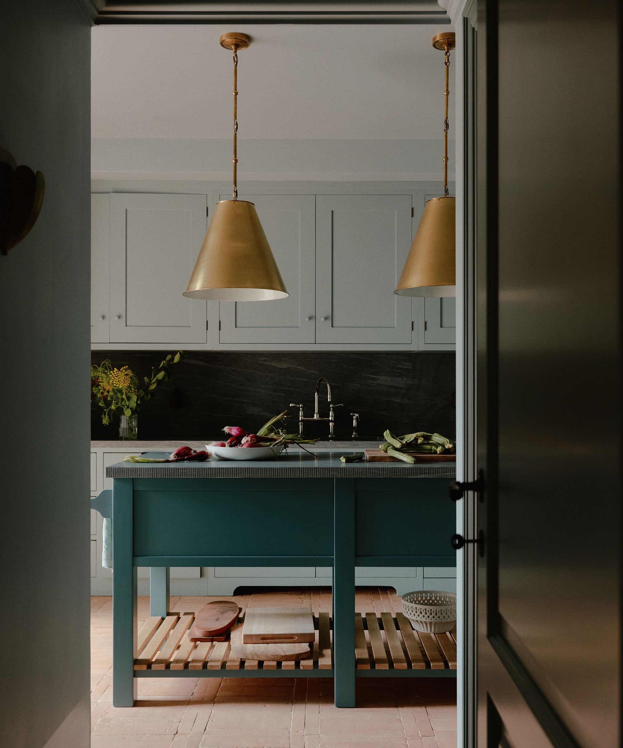 Cuisine bleu pâle avec îlot de cuisine bleu foncé et lampes dorées