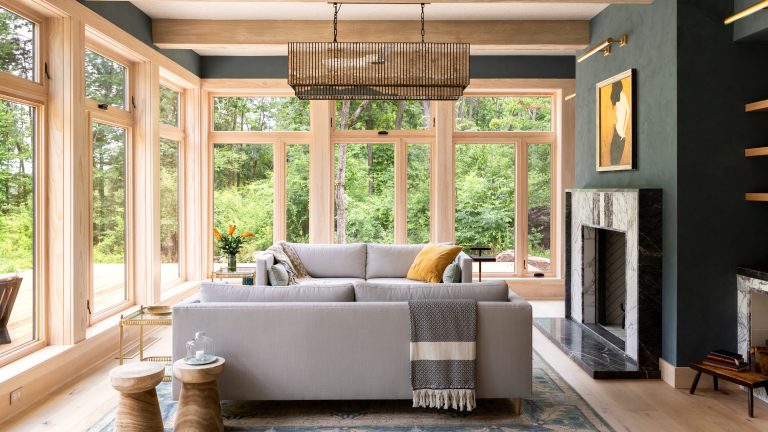 Pouvez-vous mettre un grand canapé dans un petit salon? Les concepteurs livrent leur verdict Living room with floor to ceiling windows, fireplace in charcoal colored wall, two facing gray sofas and area rug below