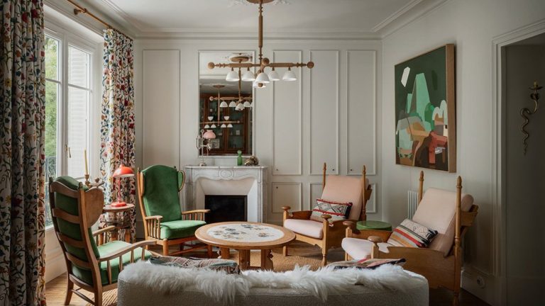 Ce nouveau style de salon est parfait si vous avez la fatigue de la décision de conception comme moi – voici pourquoi j’embrasse le médimalisme dans mon salon Eclectic living room with wood armchairs and round coffee table, abstract art and fluffy sofa