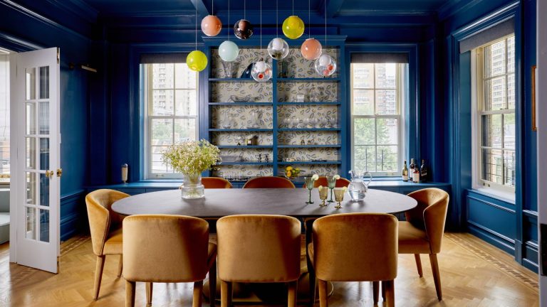 Comment ce designer d’intérieur s’est attaqué en ayant une salle de jeux au centre même de cet appartement coloré de Manhattan – il devait être un équilibre de «beau et fonctionnel» blue dining room with bauble lights and gold chairs