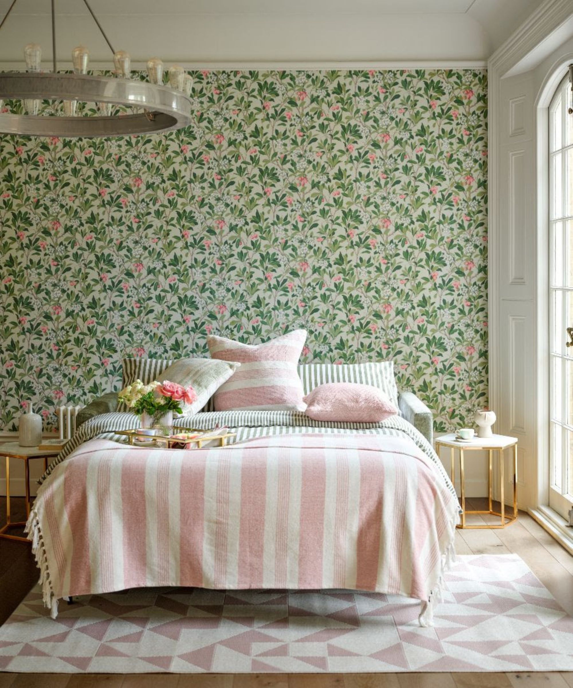 Une chambre avec un mur d'accent de papier peint à fleurs vert et un lit avec une literie rose à rayures.