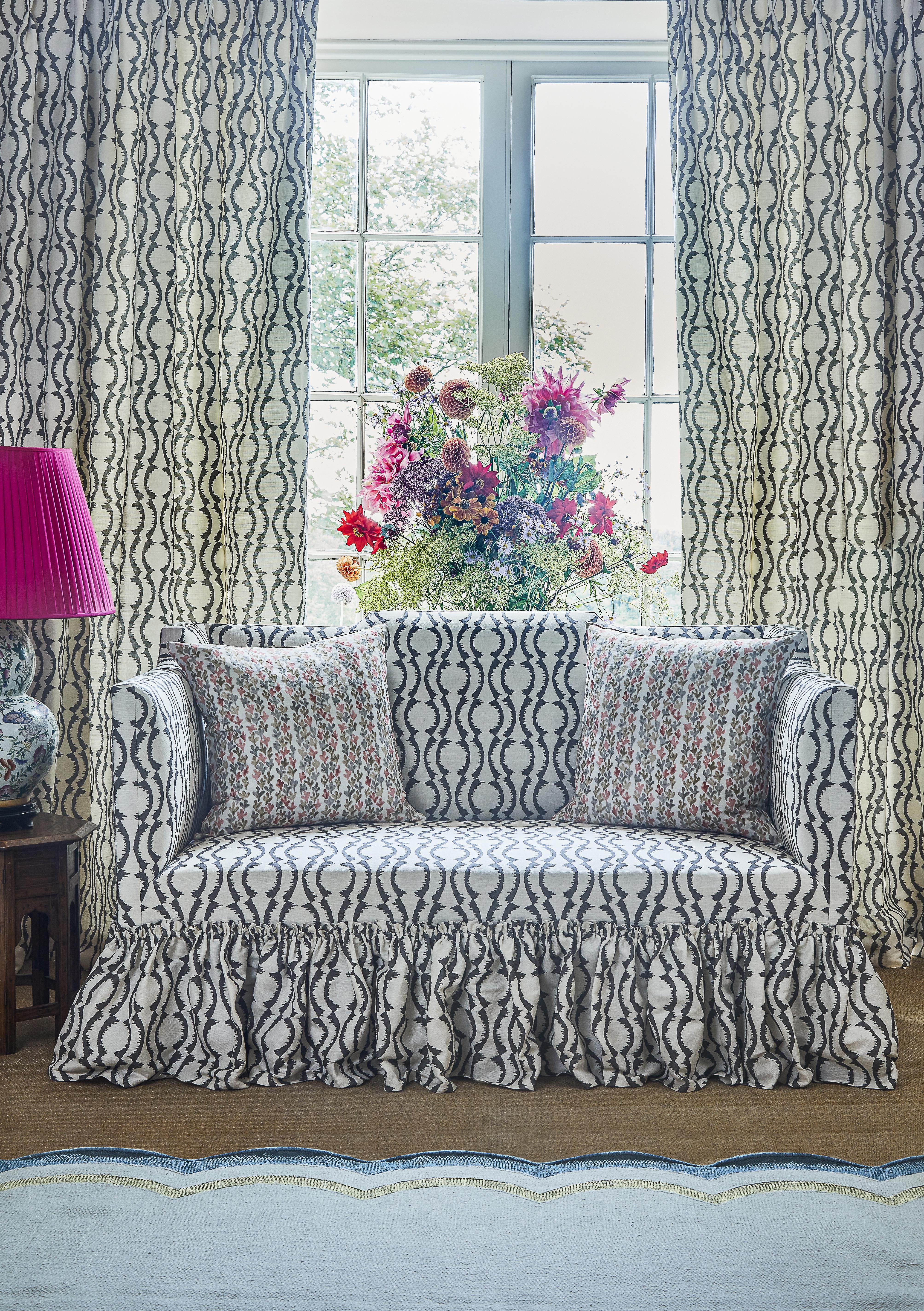 canapé et rideaux assorties, imprimé festonné graphique noir, fioritures / volants sur le canapé, fleurs, lampe de table avec teinte rose, tapis feston