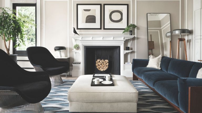 Minimalist living room with monochrome scheme, velvet sofa, black armchairs, wall art, fireplace with wood and cream ottoman