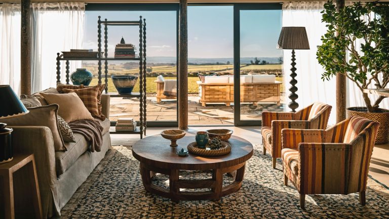 Je laisse Chatgpt déterminer ma liste de tâches de désencombrement – et cela a complètement changé la façon dont je structure ma journée A maximalist living room with floor to ceiling glass doors out onto a patio with wicker outdoor furniture.