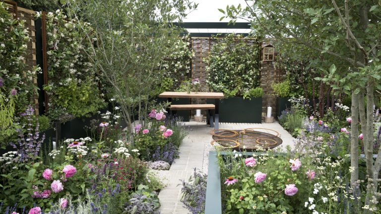 7 plantes à tailler en mai – ces arbustes et vivaces fleuriront abondamment en cas de réduction ce mois-ci A modern garden with raised beds, seating area, and beds filled with flowers and shrubs