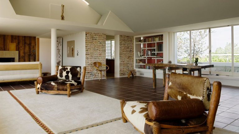 A large open plan room with two cow print chairs