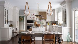 Une cuisine fatiguée a été repensée dans l’espace le plus classique – et il prouve que le blanc est toujours la couleur la plus intemporelle que vous puissiez choisir A white kitchen with classic shaker cabinets, a copper range hood, a wooden table, and marble countertops