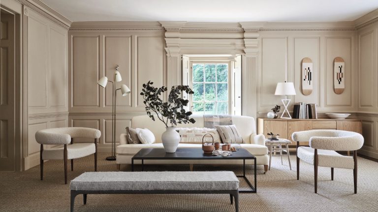 « Une stratégie de sortie pour l’encombrement » – 7 façons faciles d’adopter le minimalisme dans un ménage occupé A neutral living room with white boucle furniture and a large black coffee table. On the table is a large white vase with green leafy stems.