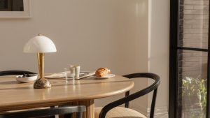 Ma table de cuisine était un dépotoir disgracieux – mais cette astuce pour acheter une lampe l’a changé complètement wooden kitchen table with gold marble and white lamp and black chairs