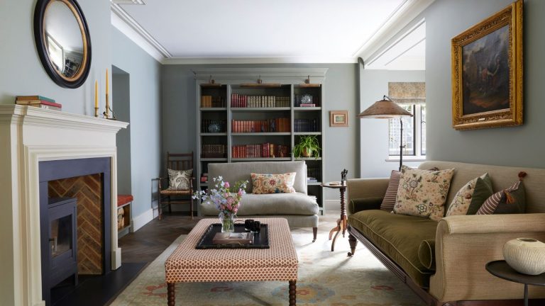 Vintage living room with fireplace, upholstered ottoman, cream sofa and vintage art and bookcase