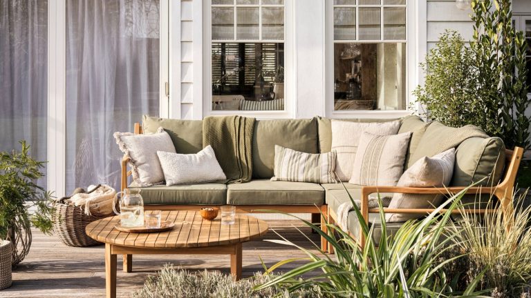 7 choses à organiser en mai 2025 – Préparez-vous en douceur aux vacances d’été et profitez du plaisir du printemps spontané Green cushions on wooden patio furniture, in front of a white panelled home.