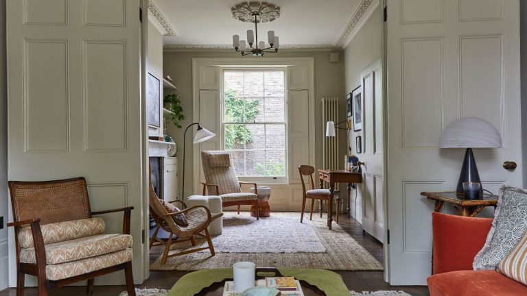 Living room with doubel doors, orange sofa, wood chairs, wood desk, woven armchairs and large carpet