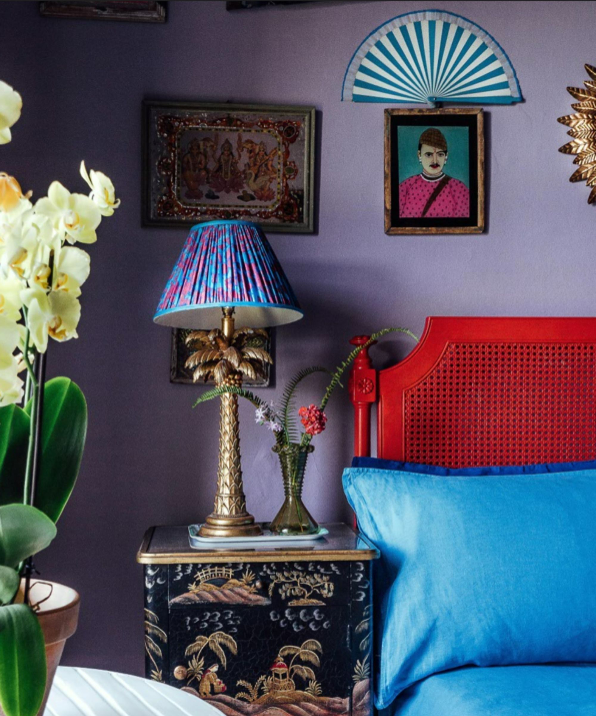 chambre maximale avec mur violet, œuvres d'art sur les murs et tête de lit rouge