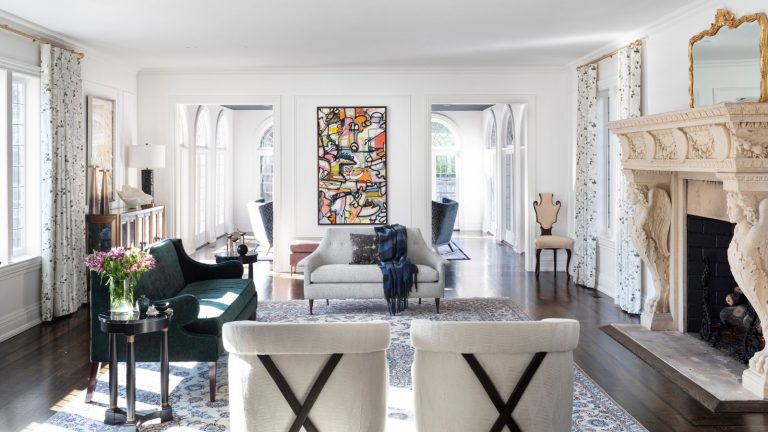 Ce gadget de 50 $ teste votre qualité d’air pour les allergènes, les polluants et la fumée nocive – en tant que rédacteur en technologie de la maison, c’est un incontournable pour tous Large, open living room with ornate fireplace, two large doorways, a patterned rug, a green sofa,a gray sofa, two chairs and abstract art on the wall, on wooden floor with white walls and ceiling.