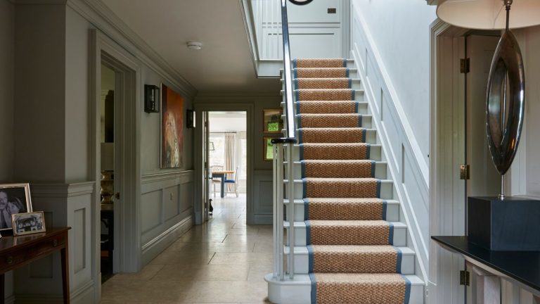 Je n’ai pas d’espace pour une salle de démarrage, donc je crée un mini sous les escaliers pour donner à mon entrée un mélange de stockage et de style – c’est ainsi que je diyt le travail light blue painted large entryway hall with painted stairs and a jute runner with blue edging
