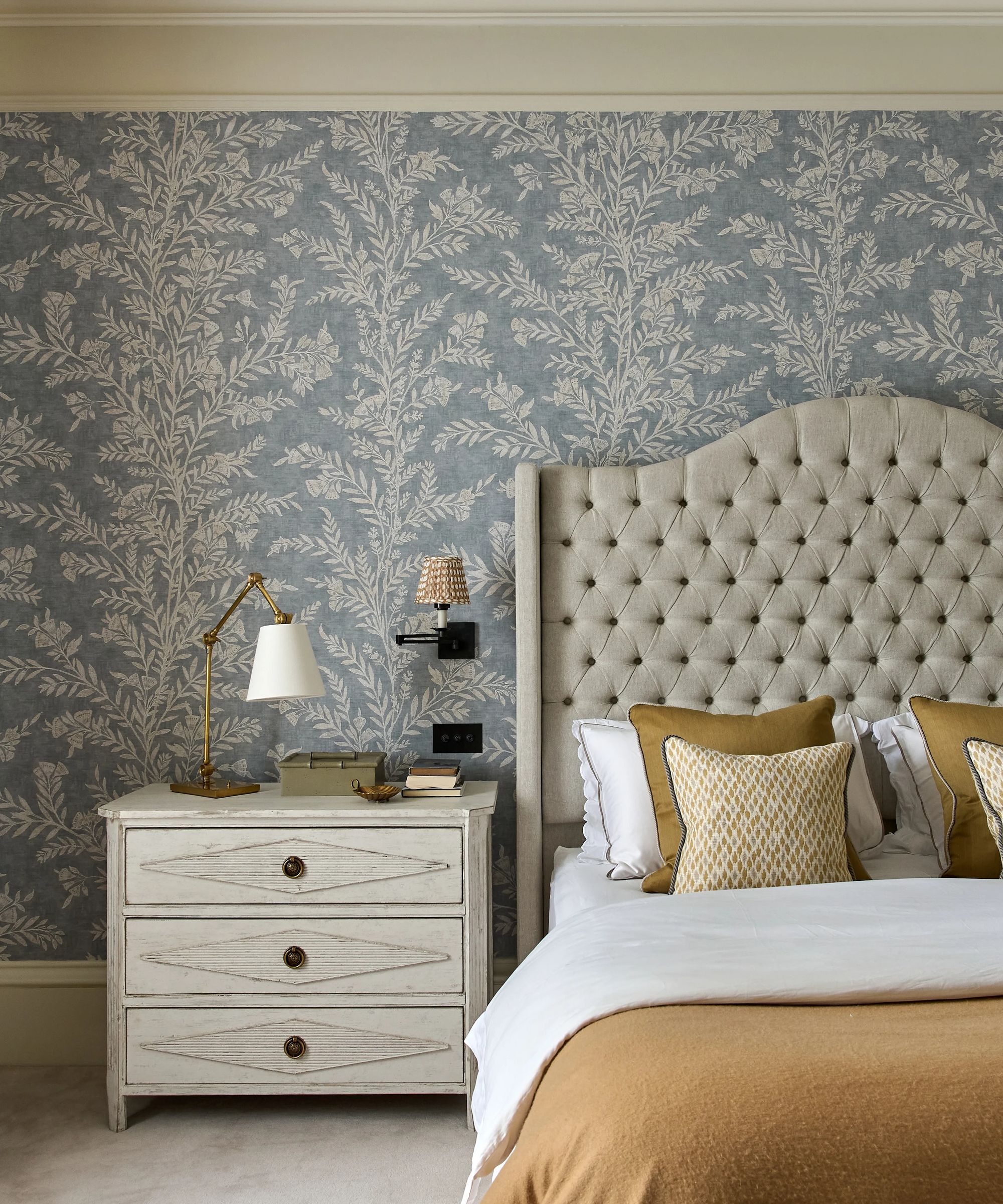 Chambre avec salon bleu floral et tête de lit arrière gris arrière avec literie orange pâle et blanche