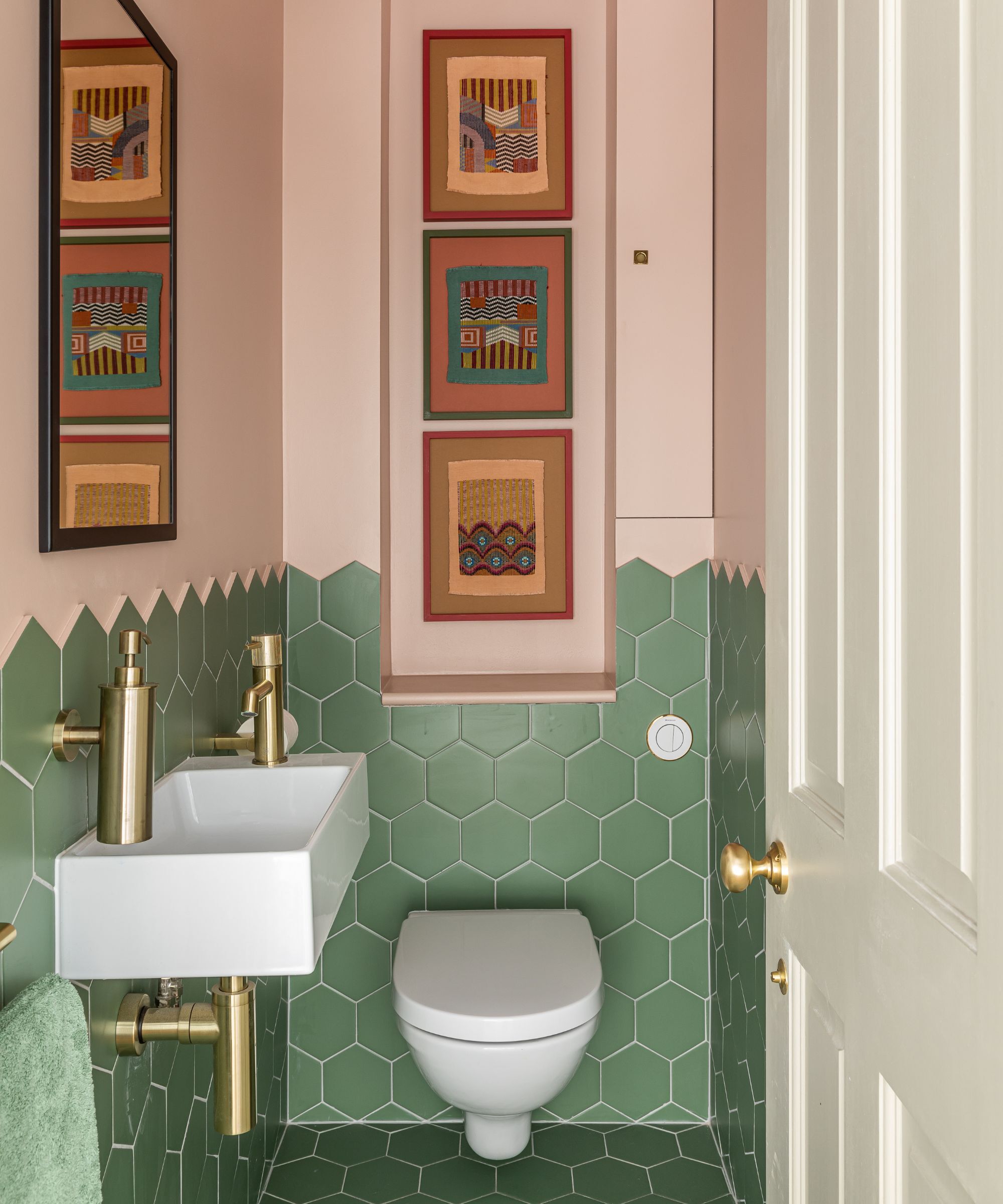 Une toilette en bas avec des murs à moitié peints dans le plâtre de réglage de farrow et de balle, l'autre moitié en carreaux hexagonaux verts.