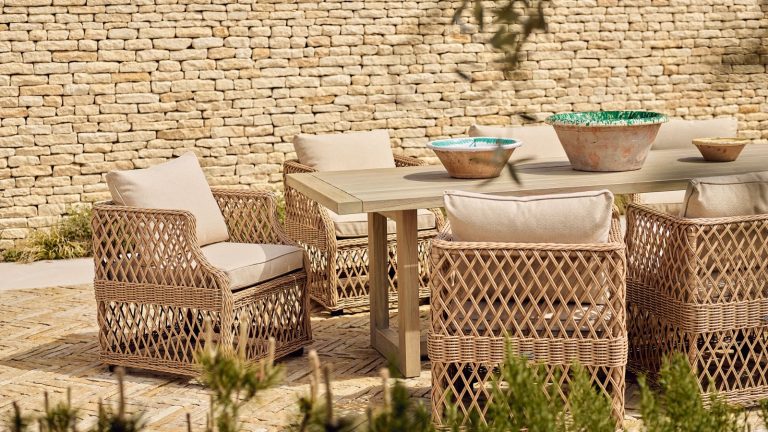 Woven wicker patio chairs around an outdoor table, on a brick patio.