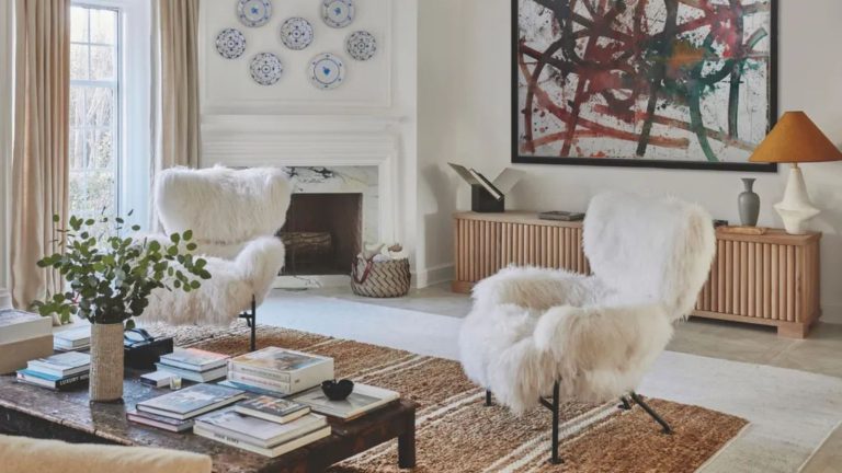 Comment savez-vous quand une pièce est terminée? J’ai demandé à 7 designers comment ils disent quand ils ont «fait» White living room with a fireplace in the corner and plates hanging above with a large jute rug, wooden coffee table and two white fur-covered chairs