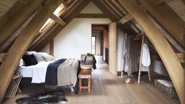 Barn extension decorated with a stylish Scandi feel. Bedroom in attic with wooden walls and double bed.
