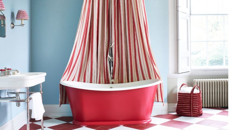 Ce 1 fruit bannit le robinet de salle de bain en déménagement sans produits chimiques – mais je me suis retrouvé avec un goût amer dans ma bouche après l’avoir essayé, voici pourquoi Bright cornflower blue and red circus theme bathroom with Victorian sink style, checkered red and white floor, retro radiator, shutters, red freestanding bath tub with red and white shower curtain