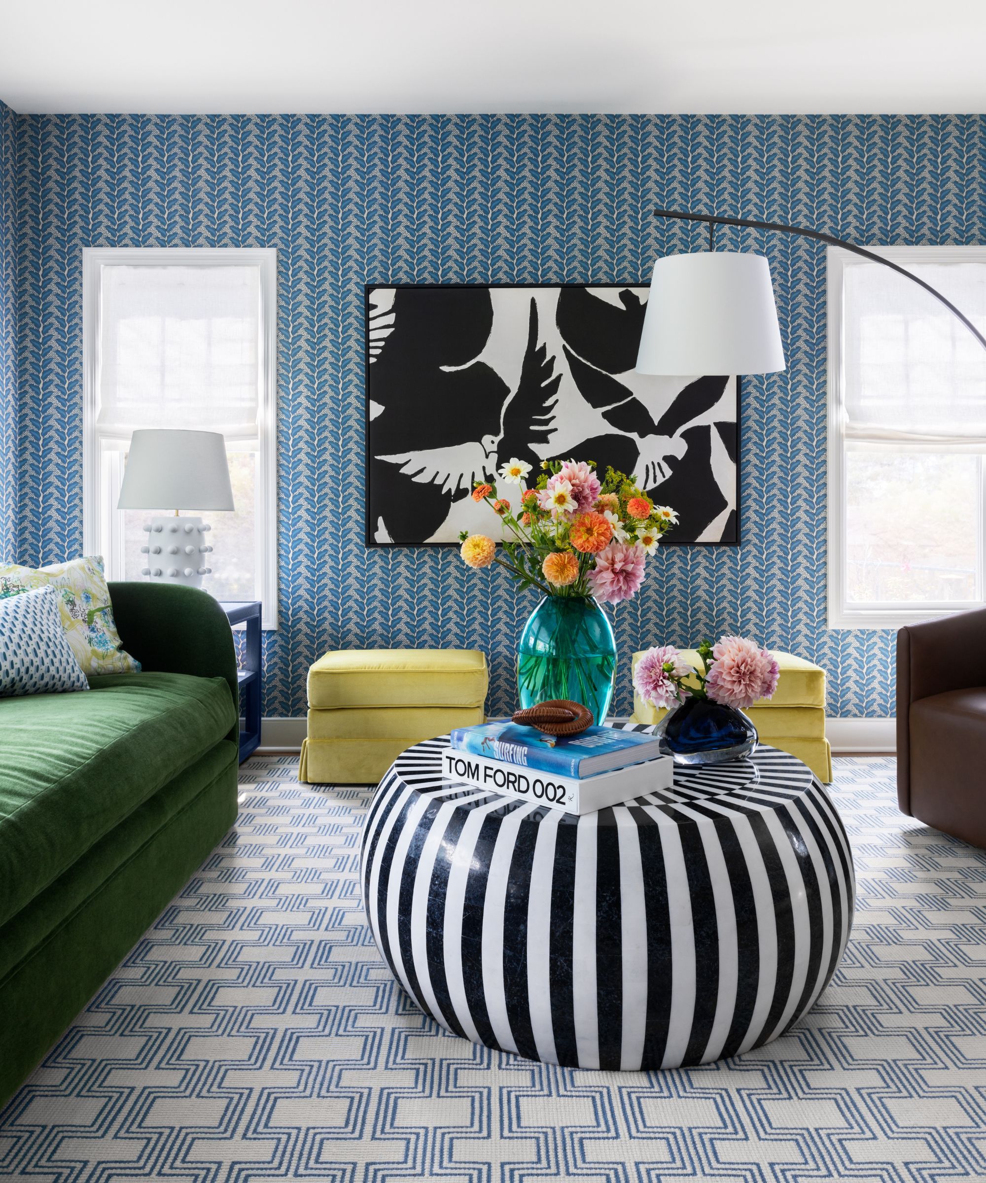 Salon avec papier peint bleu, canapé vert, table basse à rayures et tapis de déclaration