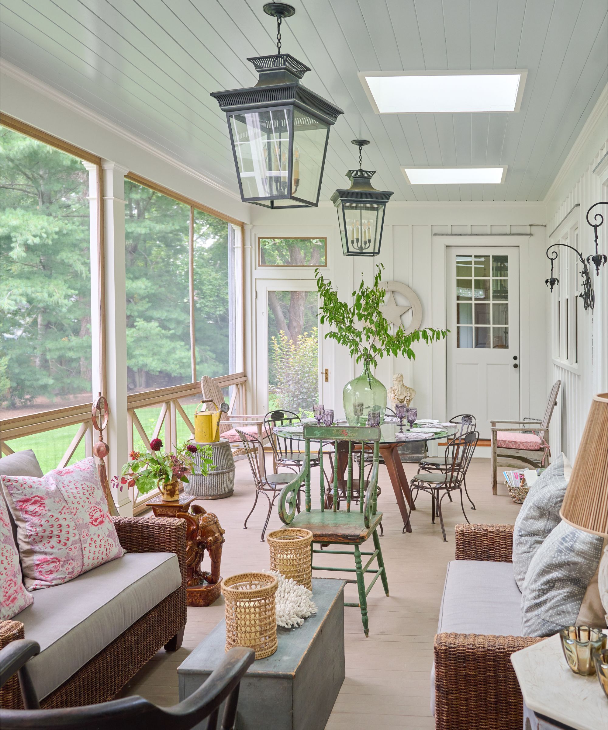 Salle de soleil lambrissée en bois blanc avec des meubles vintage et un coin repas et des sièges