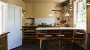 Yellow kitchen with freestanding units, hanging rails, stools, white countertops and island