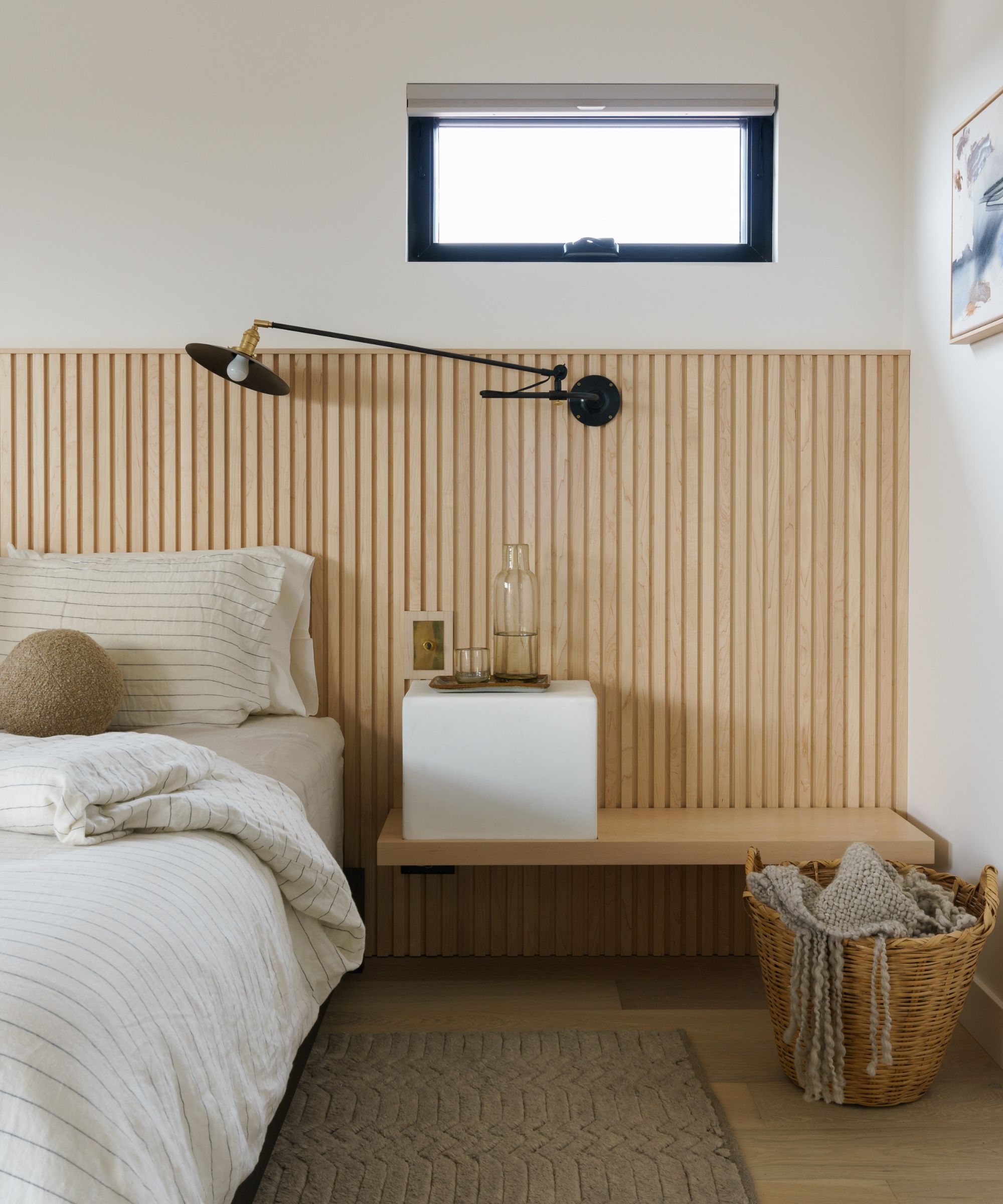 Une chambre neutre avec un tapis brun clair et des boiseries sur le mur