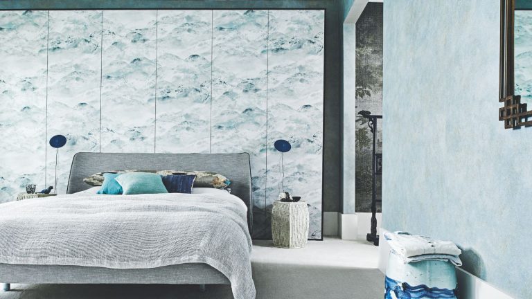 C’est le niveau d’humidité idéal pour votre chambre pour une nuit de sommeil confortable, demandez à HVAC professionnels A blue bedroom with a grey double bed, statement wallpaper wall, two matching blue lamps and a blue patterned stool.