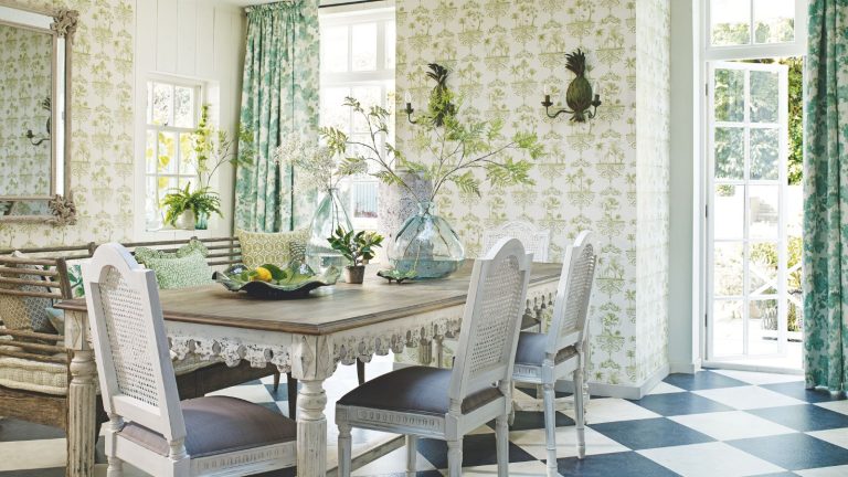 Bombes d’insectes 101 – Que sont-ils, comment les utiliser et les mesures de sécurité incontournables pour garder à l’esprit A statement dining area with green patterned wallpaper, a large dining table with white rattan chairs, green patterned curtains, black and white tiled flooring and an open door to a leafy, sunny garden. A statement mirror is seen to the right above a wooden bench with green patterned cushions.