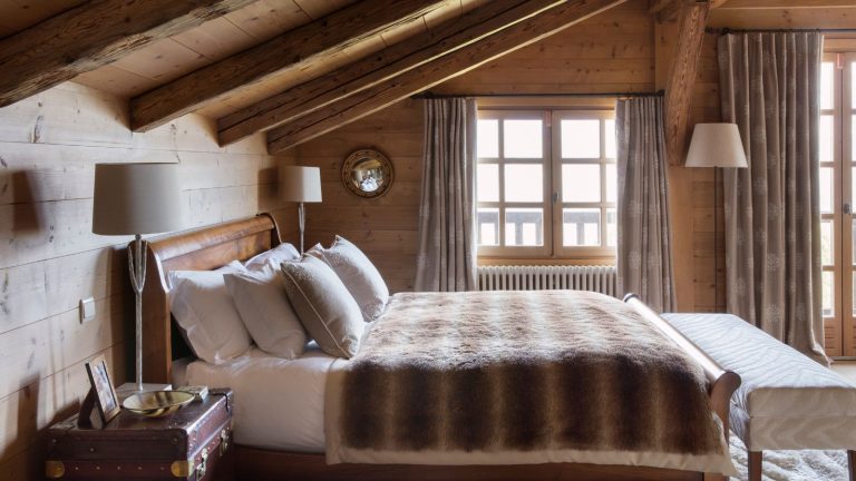 A wooden panelled attic conversion with a rustic bed.