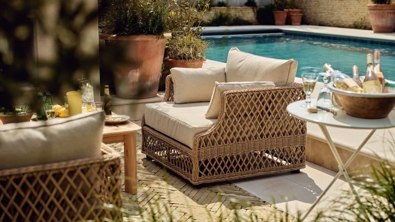 Comment réparer une piscine nuageuse – 5 méthodes Un expert en piscine dit que l’eau invitera et nettoiera à nouveau en un rien de temps A woven wicker outdoor chair on a paved patio beside a large rectangular pool.
