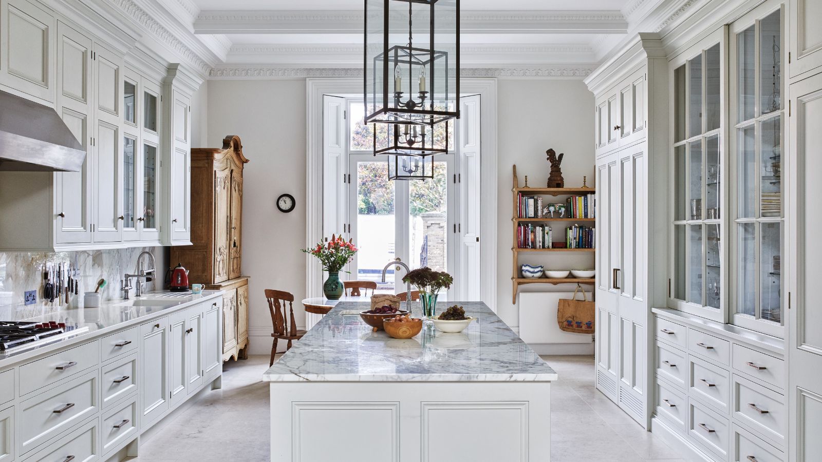 Cuisine avec armoires blanches et tiroirs intégrés, îlot avec comptoir en marbre et pendentif avec commode vintage
